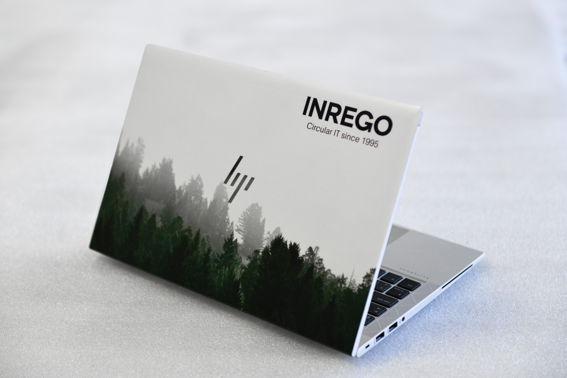 HP laptop med Inrego-logga och skogsmotiv på baksidan av skärmen.