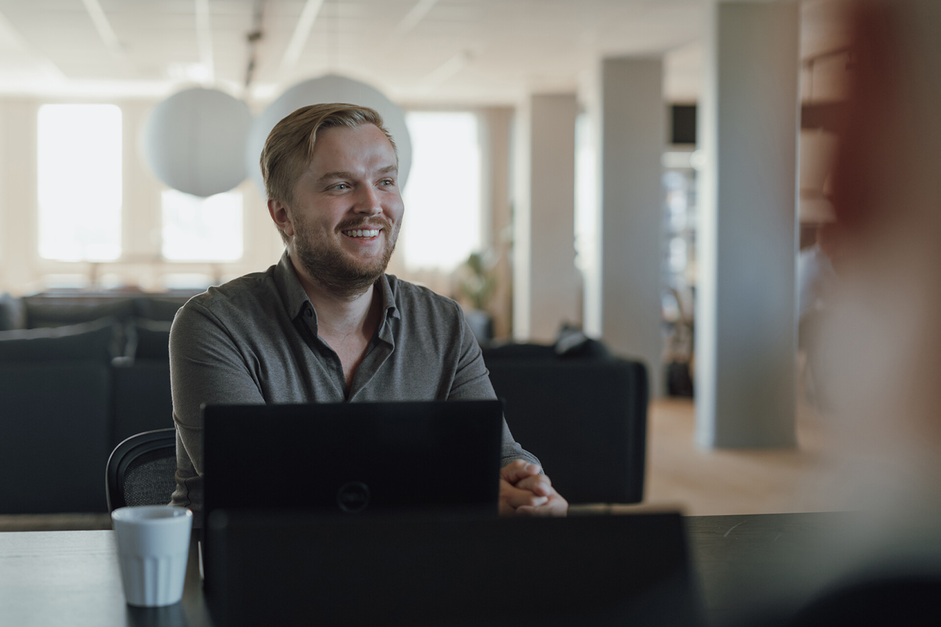 Leende blond man med laptop på kontor.